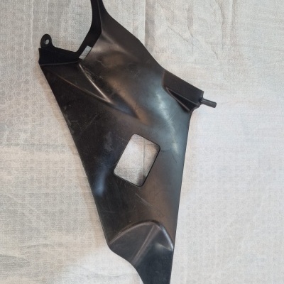 Peça plástica preta irregular com recorte quadrado sobre superfície branca