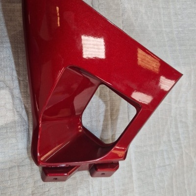 Peça automóvel vermelha metálica brilhante sobre tecido branco