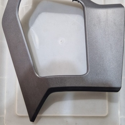 Peça plástica cinza escura angular sobre superfície plástica branca