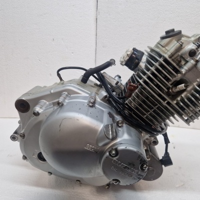 Motor de moto metálico prateado com inscrições SUZUKI OIL FILTER