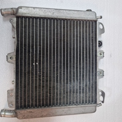 Radiador automóvel metálico preto e prateado sobre superfície branca