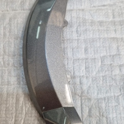 Peça metálica prateada curva sobre superfície texturada cinza