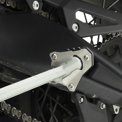 Braço oscilante prateado ligado a roda preta de moto com corrente metalica