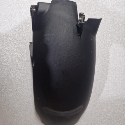 Peça de plástico preta curva sobre superfície branca texturada