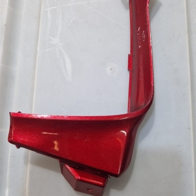 Peça automóvel vermelha metálica sobre superfície branca