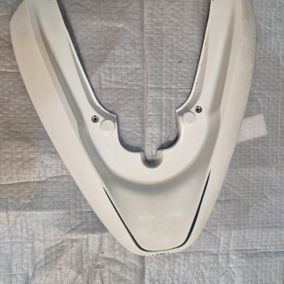 Peça plástica branca em forma de V sobre superfície cinza texturizada