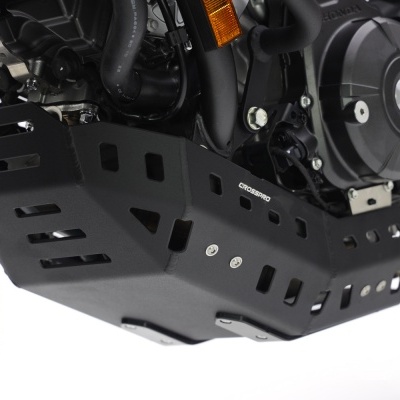 Proteção metálica preta para motocicleta com várias aberturas, parafusos visíveis e motor ao fundo