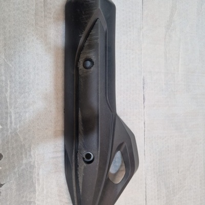 Peça plástica preta com furos e desgaste sobre tecido branco