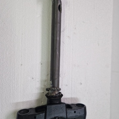 Peça metálica cilíndrica com base preta contra parede branca