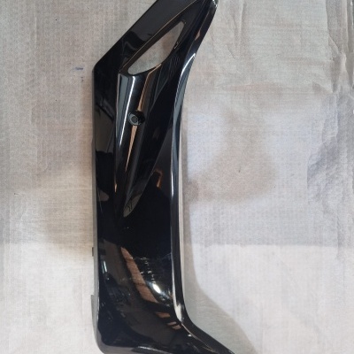 Carcaça lateral preta brilhante de peça de motocicleta sobre tecido branco