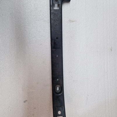 Barra metálica preta com perfurações sobre fundo branco texturado