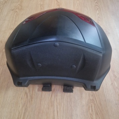 Mala para moto preta com luzes vermelhas sobre chão de madeira clara