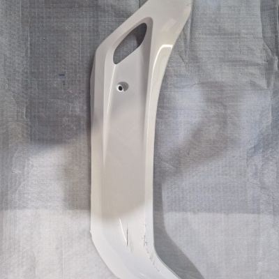 Peça plástica branca para carroçaria sobre tecido cinza