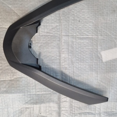 Peça plástica preta angular em superfície branca texturizada