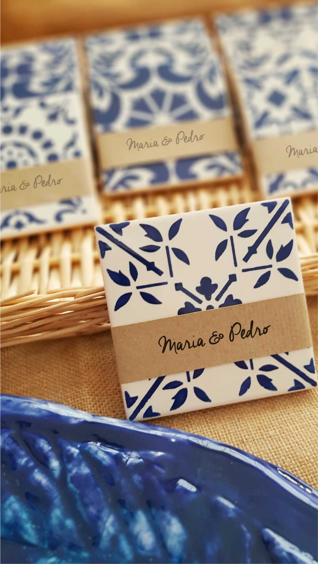 Sabonetes com padrão azul e branco, etiquetados com 'Maria & Pedro', sobre cesta de verga e tecido castanho