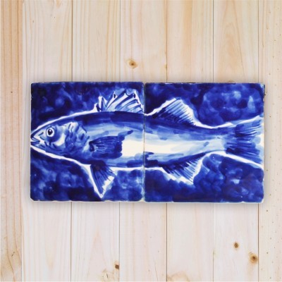 Dois azulejos azuis e brancos com desenho de peixe sobre madeira clara