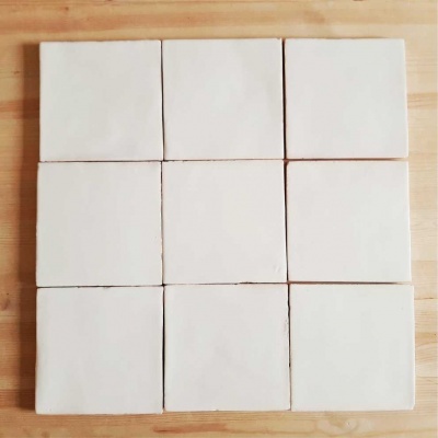 Nove azulejos brancos quadrados sobre superfície de madeira clara