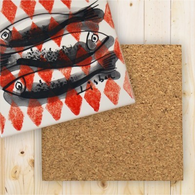 Pano de cozinha com estampa de peixes e padrão vermelho sobre cortiça e fundo de madeira