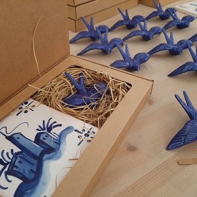 Estatuetas azuis em forma de pássaros e bloco decorado com padrão azul numa caixa de papelão.