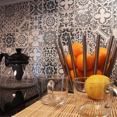 Cozinha com azulejos decorativos, jarro de vidro, taça e tigela com frutas.