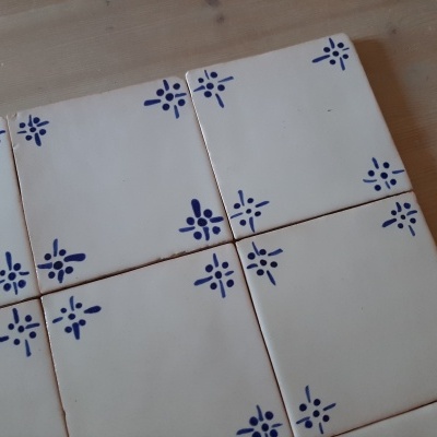 Azulejos cerâmica branca com padrão azul nos cantos sobre madeira clara