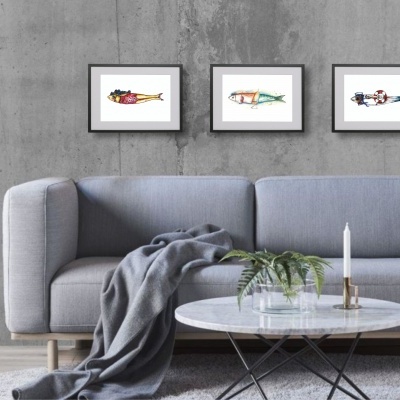 Sala de estar com sofá cinza, mesa redonda branca, candeeiro de pé e três quadros na parede cinza de cimento.