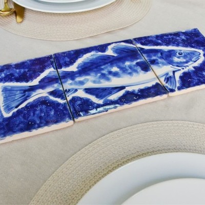 Três azulejos cerâmicos pintados à mão com desenho azul de um peixe