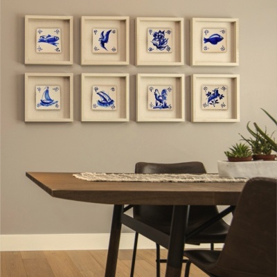 Conjunto de azulejos decorativos azuis em molduras claras na parede de sala de jantar.
