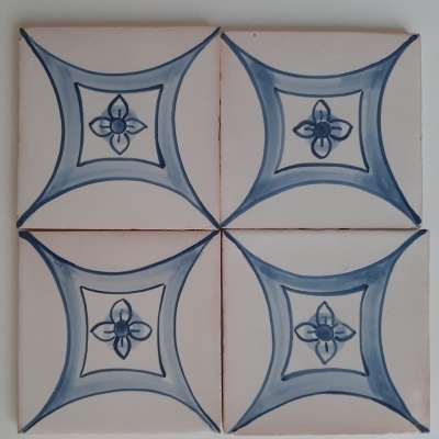 Quatro azulejos brancos com padrão azul geométrico e flor estilizada ao centro