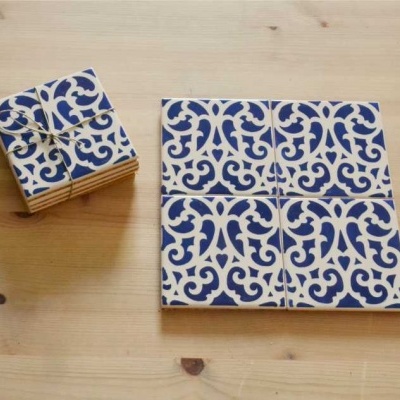 Azulejos decorativos quadrados padrão azul e branco sobre madeira clara.