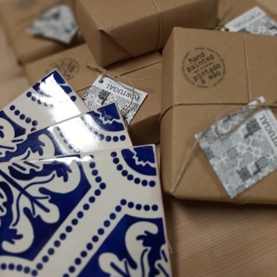 Blue and white ceramic tiles next to wrapped brown packages with tags and hand painted stamp