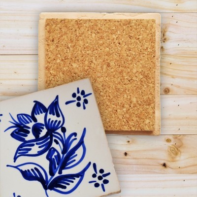 Dois azulejos quadrados, um com padrão floral azul sobre branco e outro com cortiça, sobre madeira clara