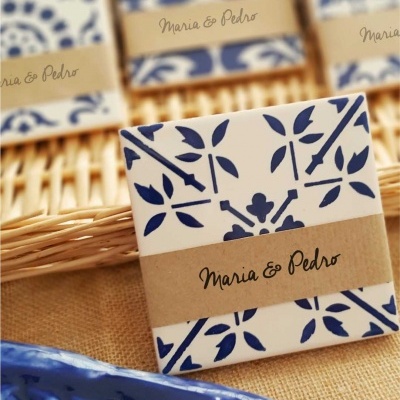 Sabonetes com padrão azul e branco, etiquetados com 'Maria & Pedro', sobre cesta de verga e tecido castanho