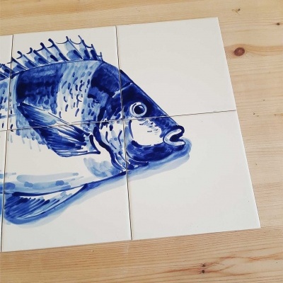 Quatro azulejos com peixe azul pintado em mesa de madeira