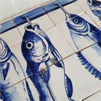Azulejos decorativos com desenho de peixes azuis sobre fundo branco