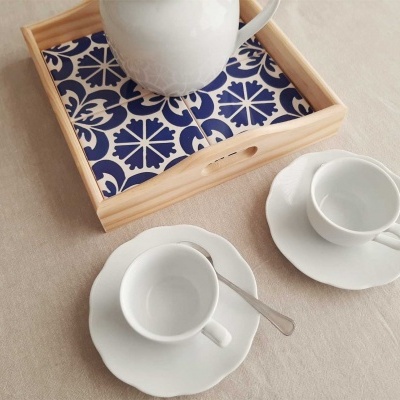 Tabuleiro de madeira com padrão azul e branco, bule branco, duas chávenas e pires brancos com colheres
