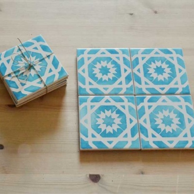 Quatro azulejos decorativos azuis e brancos sobre superfície de madeira