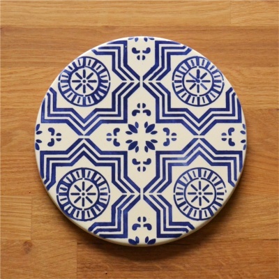 Prato cerâmico redondo com padrão geométrico azul e branco sobre superfície de madeira
