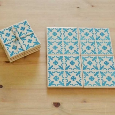 Azulejos quadrados com padrão azul e branco sobre mesa de madeira clara