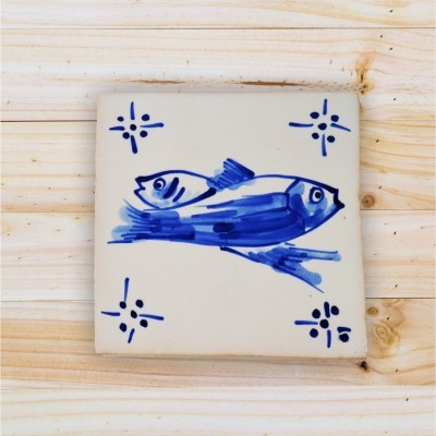 azulejo de cerâmica com desenho azul de dois peixes e símbolos decorativos