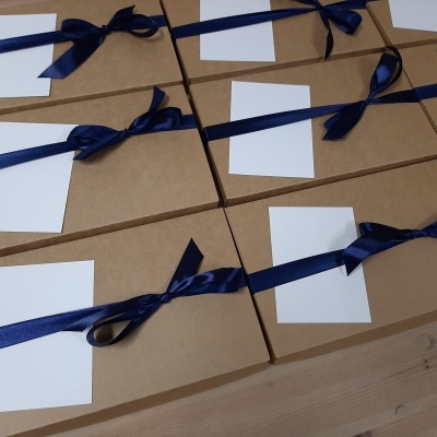 Caixas de cartão castanho claro com fitas de cetim azul escuro e etiquetas brancas sem texto