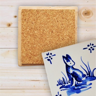 Suporte de cortiça com azulejo decorativo azul e branco sobre madeira clara