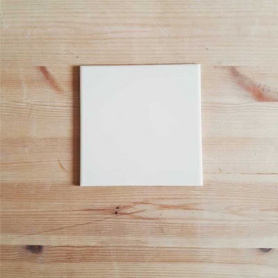 Azulejo branco quadrado sobre mesa de madeira clara