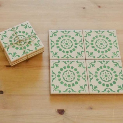 Azulejos quadrados verdes e brancos com padrão mandala sobre mesa de madeira clara