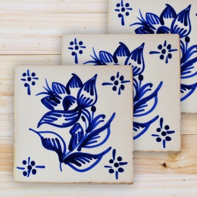 Três azulejos quadrados com padrão floral azul em fundo branco