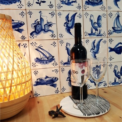 Garrafa de vinho, copos, abajur de vime e azulejos tradicionais azuis e brancos