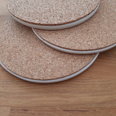 Bases redondas para copos em cortiça com bordas brancas sobre mesa de madeira