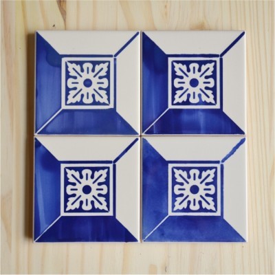 Conjunto de quatro azulejos cerâmicos azul e branco com padrão geométrico sobre superfície de madeira clara