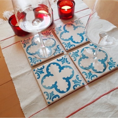 Quatro azulejos quadrados decorativos azul e branco com copos de vinho e velas vermelhas