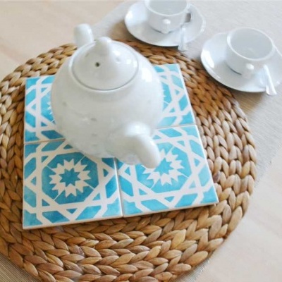 Conjunto de chá branco com azulejos azuis sobre suporte de fibra trançada